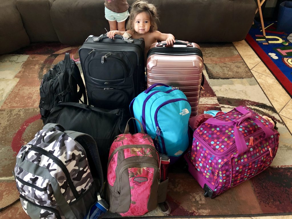 The toddler hanging out with all our luggage at home before we load up the car. 